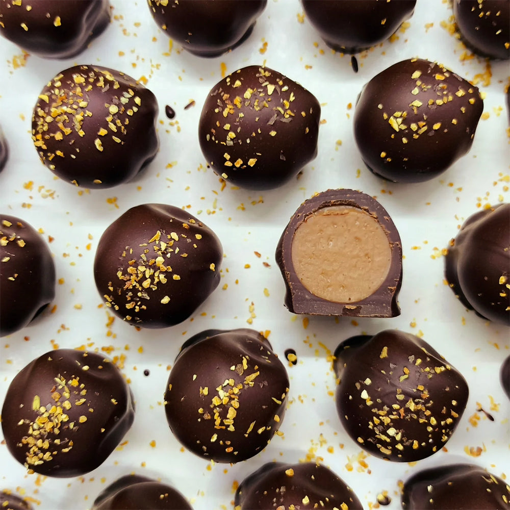 Chocolate truffles with gold sprinkles on a white background