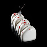 White meringue cookies with red spots and a metal skewer on a black background