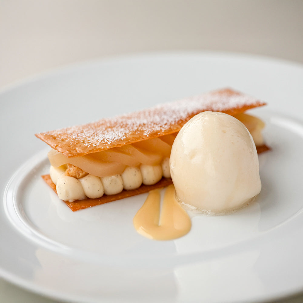 Delicate dessert with a shell, cream, and sauce on a white plate
