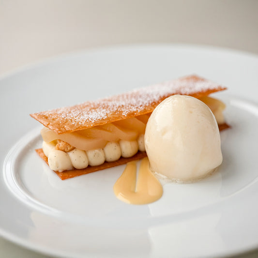 Delicate dessert with a shell, cream, and sauce on a white plate