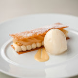 Delicate dessert with a shell, cream, and sauce on a white plate