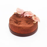Round chocolate cake with pink flowers on a white background