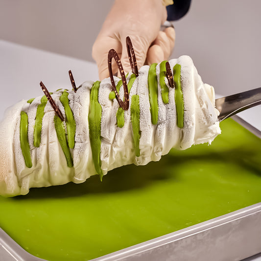EVS09021_Pistachio_Gourmet_Variegato_for_Gelato_Pastry_6kg_Bella_Verde Ice cream dessert with green drizzle and chocolate sticks on a green surface