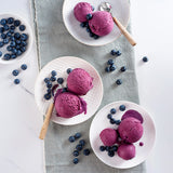 EVS10061_Blueberry_Flavour_Paste_for_Gelato_3.5kg_Pasta_Mirtillo Purple ice cream scoops on white plates with blueberries on a light gray cloth.