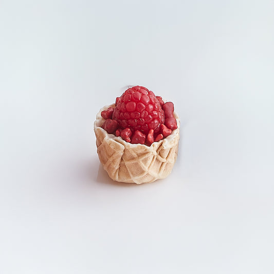 Waffle cone filled with raspberries on a light gray background