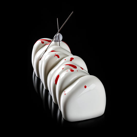 White meringue cookies with red spots and a metal skewer on a black background
