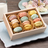 Box of colorful macarons on a light blue plate with a glass of milk.
