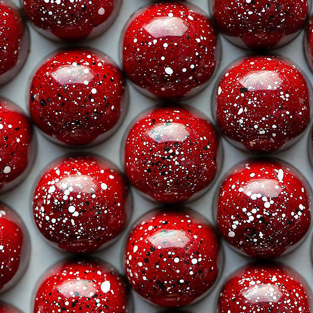 Close-up of red spherical bon bons with a speckled pattern on a white background