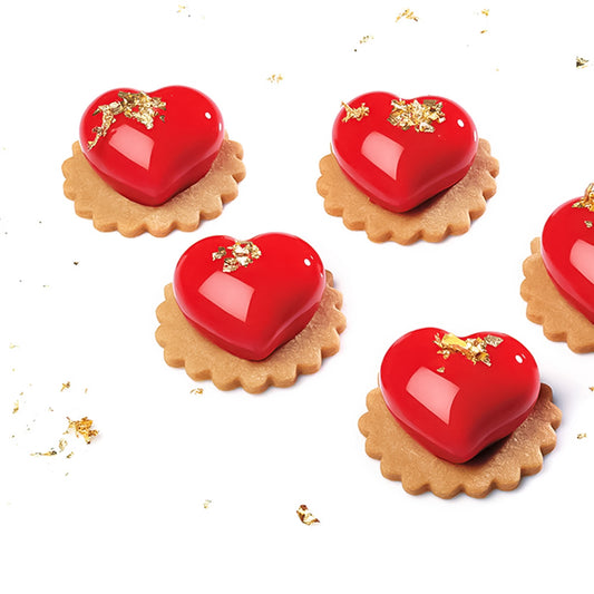Heart-shaped red candies on cookies with gold accents on a white background